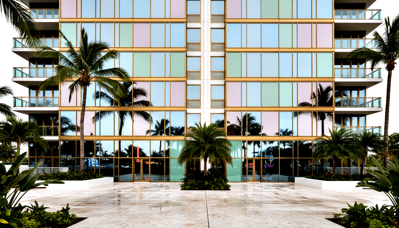 Building facade with mint-green and pink glass curtain wall panels, gold framing, white balconied wings, palm-lined marble plaza.