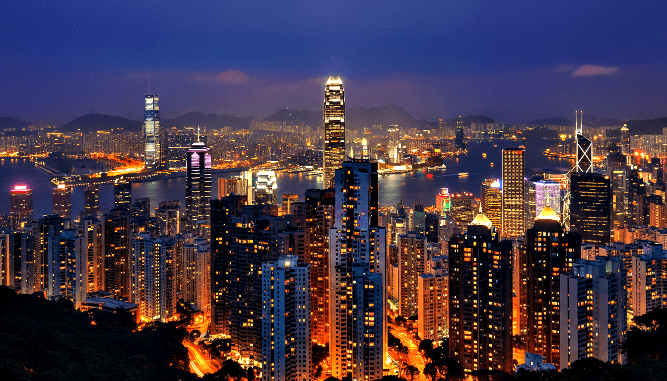 Night panorama: dense urban skyline with tapered glass apex tower, diamond-facade tower, harbor, bridge, dark mountains under navy sky.
